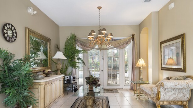 A spacious living room with a chandelier, a sofa, a coffee table, and a large potted plant. - Closest to Disney by VillaDirect (Kissimmee)