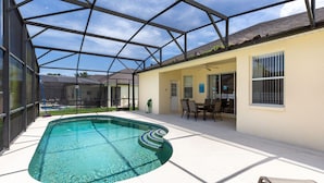 A covered outdoor swimming pool with a patio area, including a table and chairs.