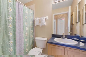 A bathroom with a toilet, sink, and shower curtain.