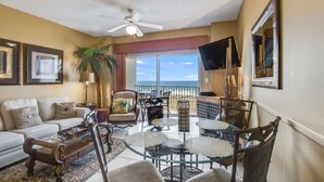 Un salon comprenant un canapé, une table basse, un téléviseur et un balcon avec vue sur l’océan.