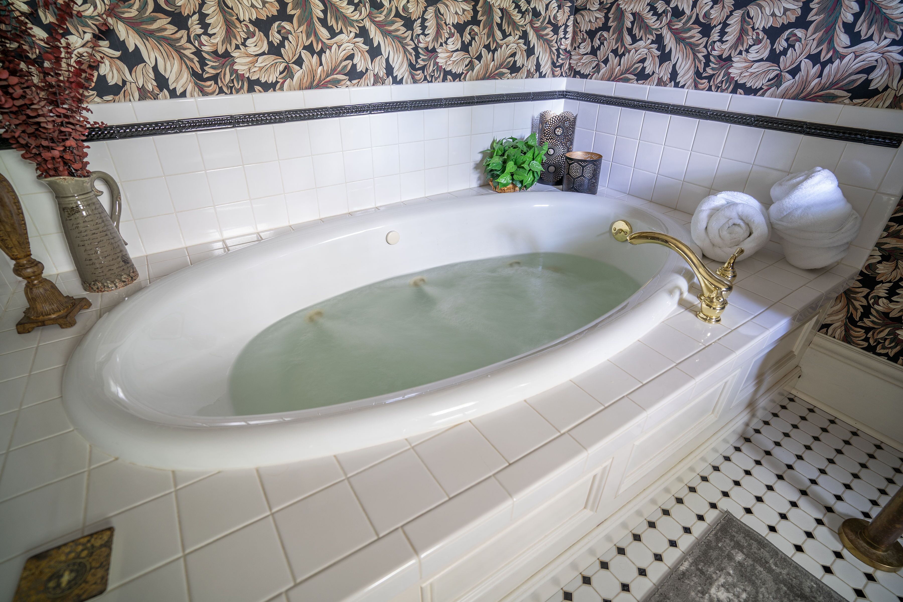 A bathtub with a gold faucet, surrounded by white tiles and a decorative border.