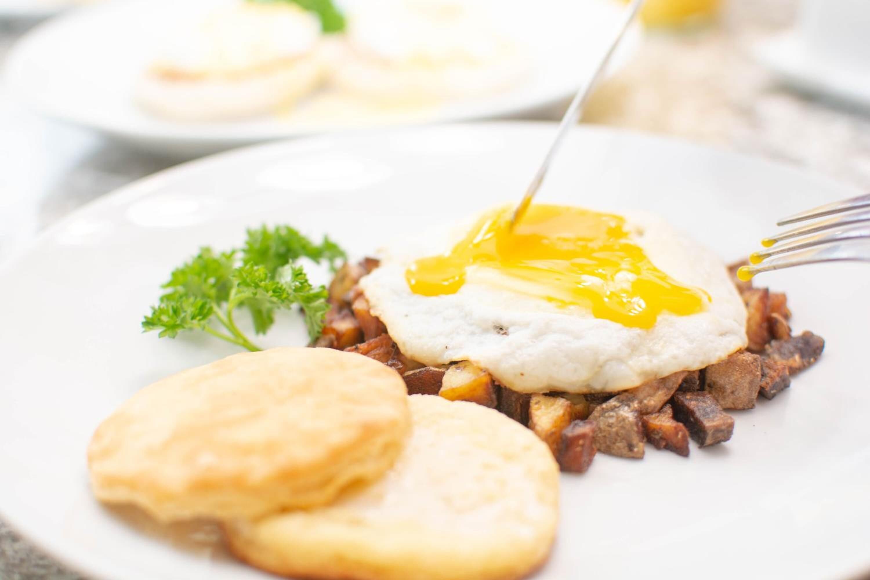 Un plato con un desayuno que incluye huevos fritos, patatas ralladas y bizcochos.