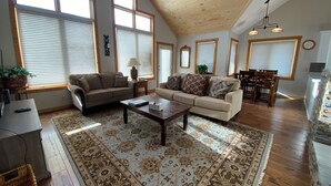 A spacious living room with a high ceiling, large windows, a wooden floor, and a patterned rug. - Getaway in CB @ the Alpine Edge Retreat! 4 bedroom Single Family Home.  (Crested Butte)