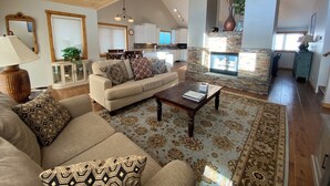 A spacious living room with a high ceiling, a fireplace, a dining area, and a kitchen in the background. - Getaway in CB @ the Alpine Edge Retreat! 4 bedroom Single Family Home.  (Crested Butte)