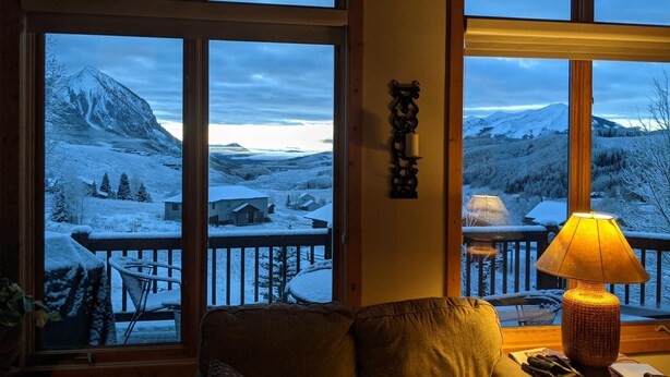 A cozy living room with a large window overlooking a snowy mountain landscape. - Getaway in CB @ the Alpine Edge Retreat! 4 bedroom Single Family Home.  (Crested Butte)