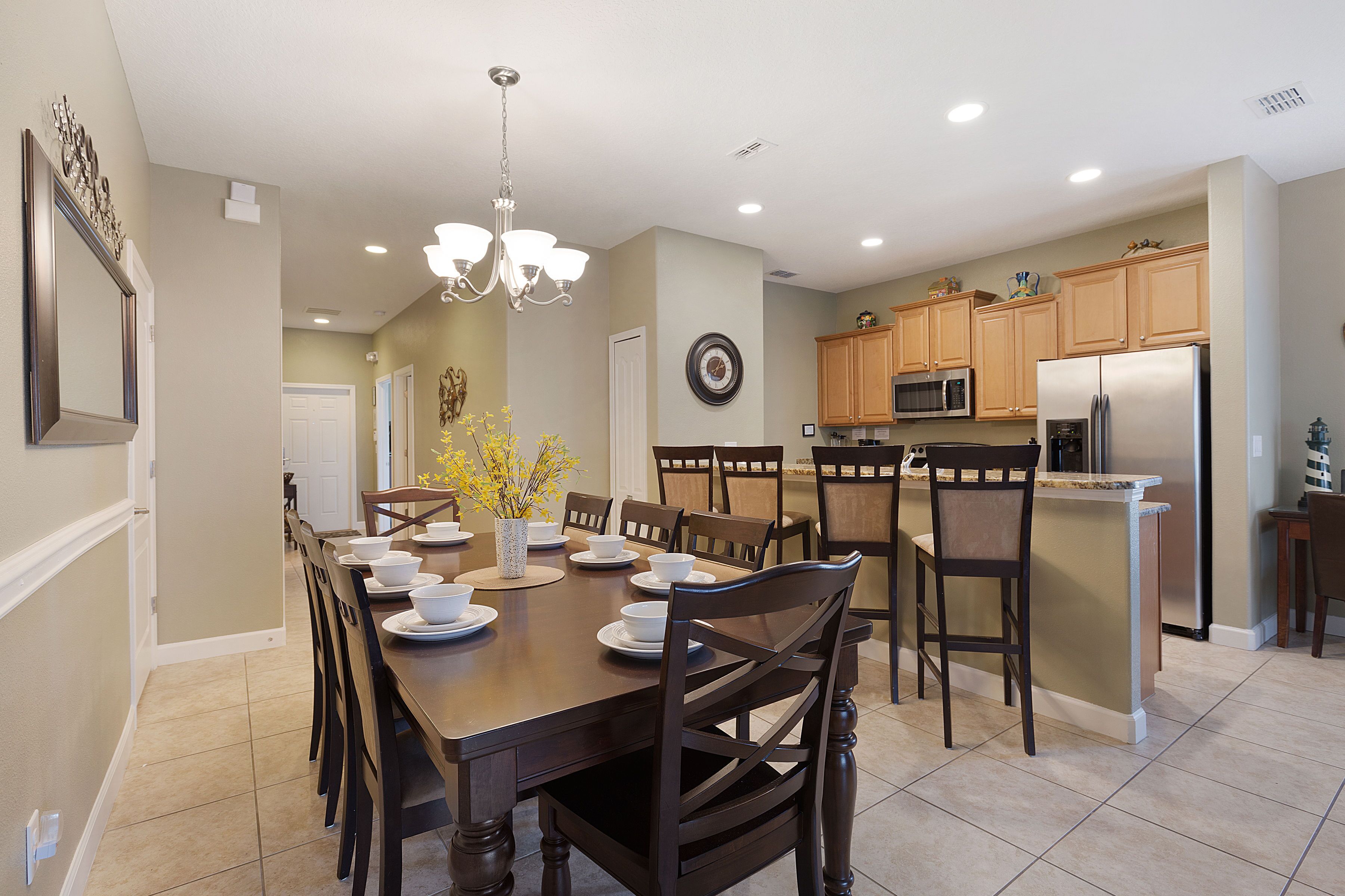A modern kitchen with a central island, wooden chairs, and a dining table set for six.
