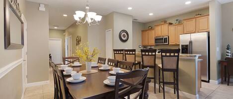 A modern kitchen with a central island, wooden chairs, and a dining table set for six.