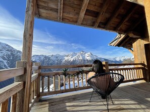 Une terrasse en bois offrant une vue sur des montagnes enneigées.