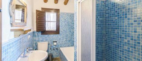 A bathroom with a sink, toilet, and bathtub, featuring blue mosaic tiles and wooden beams.