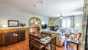 A spacious living area with a dining table, sofa, and a fireplace. - Mirador de Cómpeta by Ruralidays (Málaga)