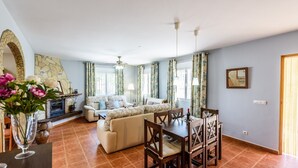A spacious living room with a fireplace, a dining area with wooden chairs, and a sofa set. - Mirador de Cómpeta by Ruralidays (Málaga)