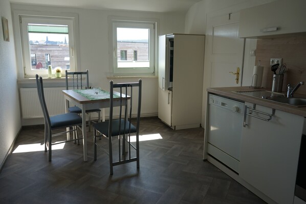 Une cuisine compacte comprenant une table et des chaises, un réfrigérateur et un lave-vaisselle.