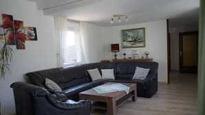 Un salón con un sofá de cuero oscuro, una mesa de centro de madera y un cuadro en la pared.