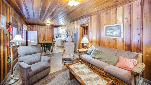 A wooden interior with a sofa, armchair, and a table with a placemat. - The Cabins at Cloudcroft (Cloudcroft)