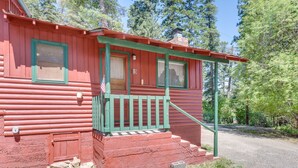 A red log cabin with a green porch and steps leading to a door. - The Cabins at Cloudcroft (Cloudcroft)