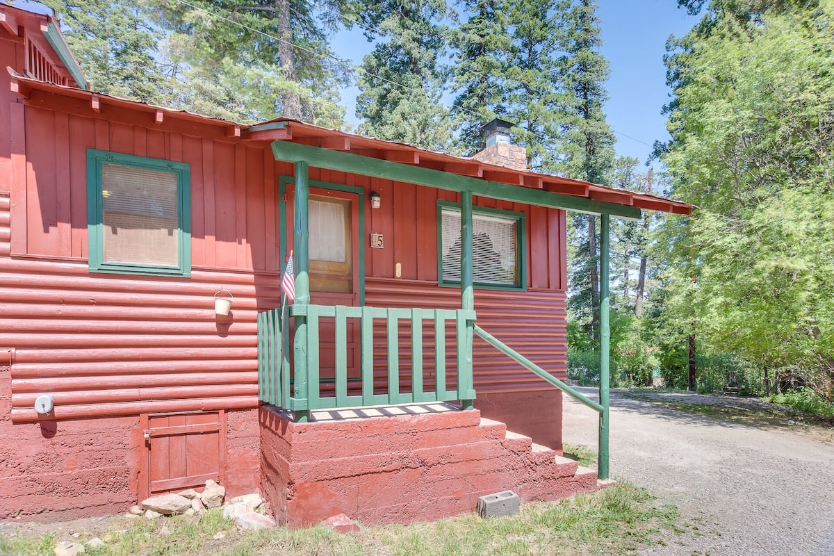 Eine rote Holzhütte mit einer grünen Veranda und Stufen, die zu einer Tür führen.