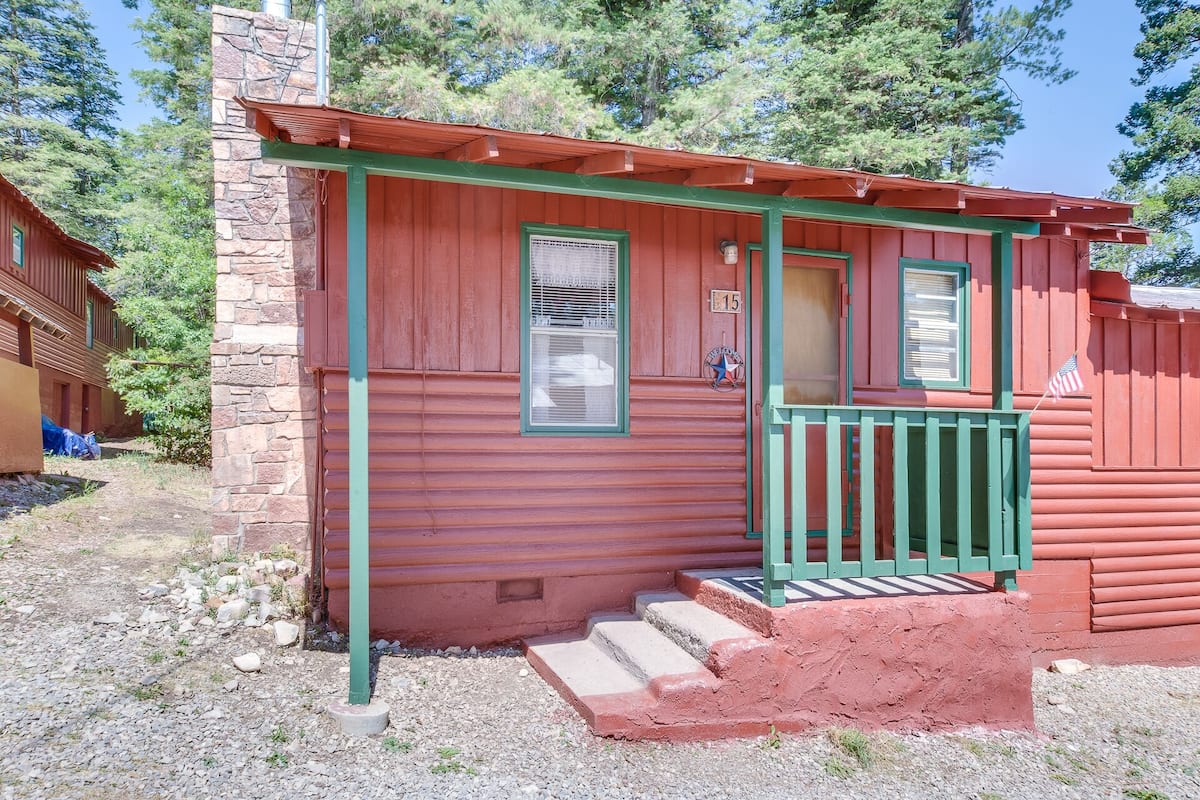 Eine rote Holzhütte mit einer grünen Veranda und Treppen, die zu einer Tür führen.