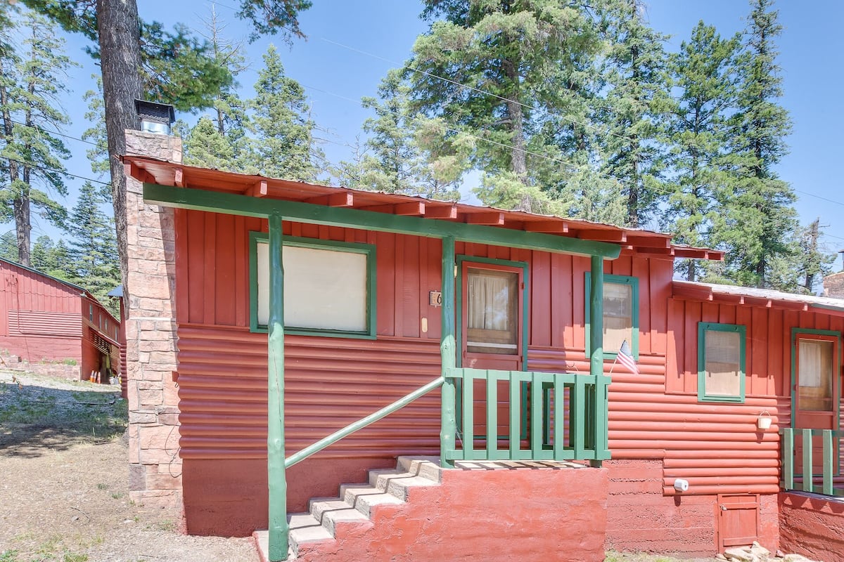 Eine rote Holzhütte mit Steinunterbau, grünen Verzierungen und einer kleinen Veranda mit Stufen zum Eingang.