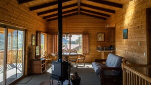Interior acogedor de una cabaña con chimenea, paredes de madera, un sofá y un comedor.