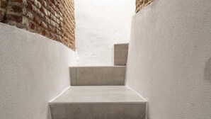 A narrow stairway with a brick wall on one side and a plain wall on the other, leading to a higher level. - Fantastic apartment in Barrio de las Letras (Madrid)