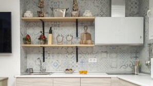 A kitchen with a white countertop, wooden cabinets, a stainless steel sink, and decorative items on shelves. - Fantastic apartment in Barrio de las Letras (Madrid)