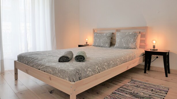 Une chambre à coucher avec un lit en bois, deux tables de chevet avec des lampes, une couvre-lit à motifs et un tapis sur le sol.