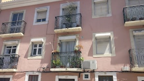 Un immeuble à plusieurs étages, doté de balcons, de climatiseurs et de portes numérotées.