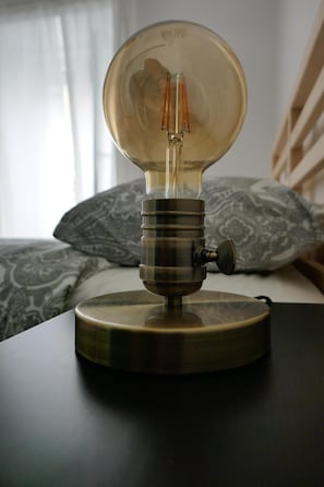 A vintage-style light bulb on a bedside table in a bedroom.