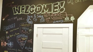 Un tableau noir sur lequel est écrit un message de bienvenue, ainsi que divers noms et formules de salutation dans plusieurs langues.