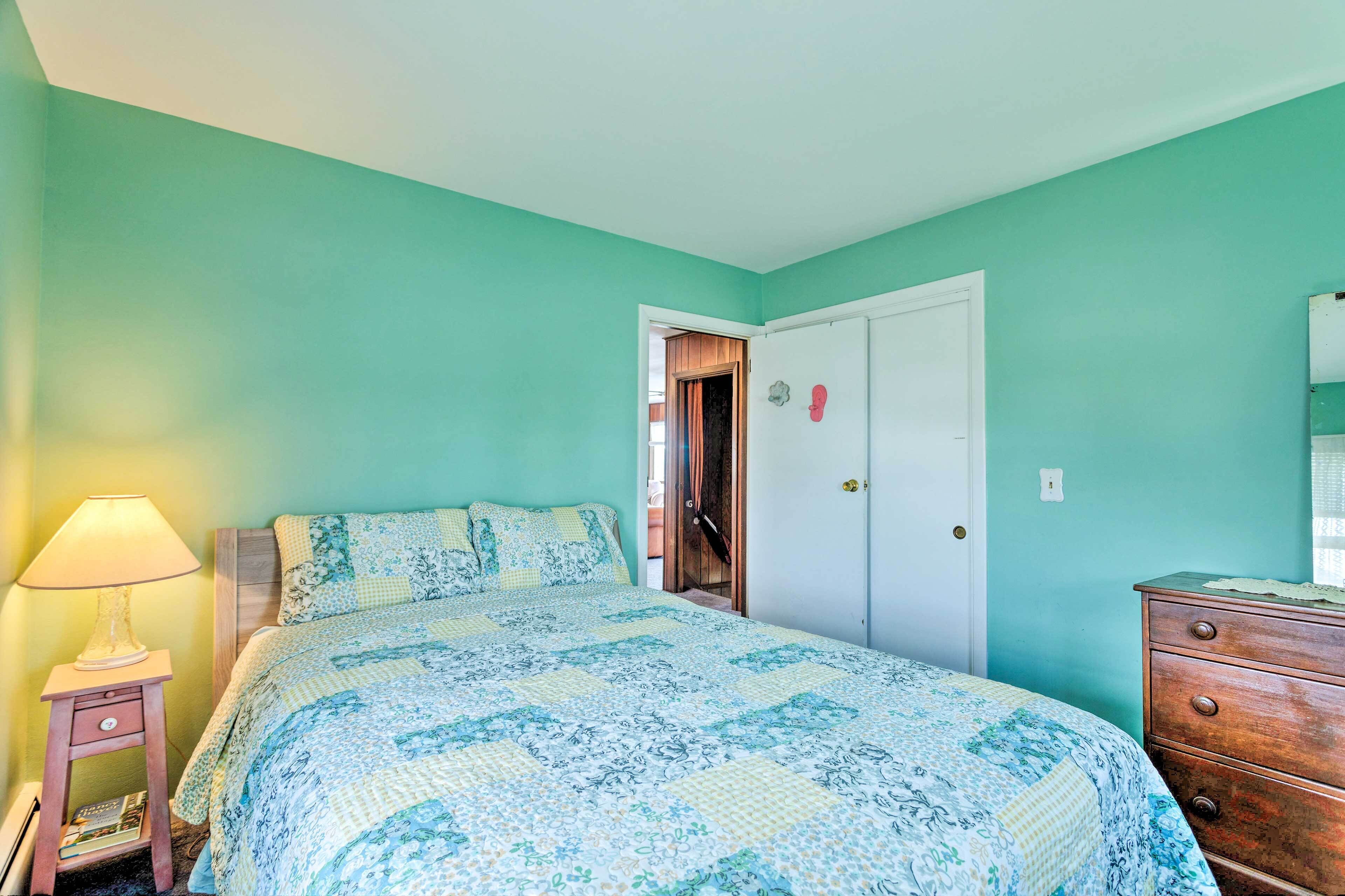 Une chambre à coucher avec un lit, une table de chevet, une commode et une porte.
