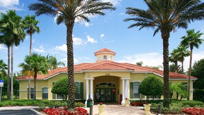 A yellow building with a red-tiled roof, palm trees, and red flowers. - The Floridian by VillaDirect (Kissimmee)