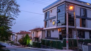 A modern hotel with a glass facade, a visible sign indicating it is a hotel, and a street view with parked cars and a sidewalk. - Sist 34 Suit Hotel (Serdivan)