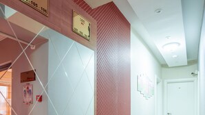 A hallway with a red wall, a tiled floor, and a door at the end. There are signs above the door indicating room numbers 104-105-106. - Sist 34 Suit Hotel (Serdivan)