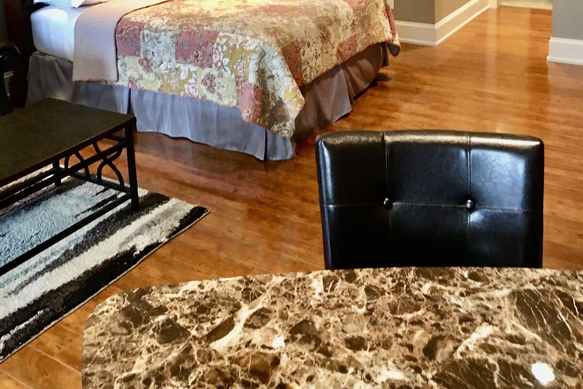 A bedroom with a bed, a nightstand, a chair, and a marble table.