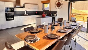 Een moderne keuken met inbouwapparatuur, een eethoek met een houten tafel en stoelen, en uitzicht op de omgeving.