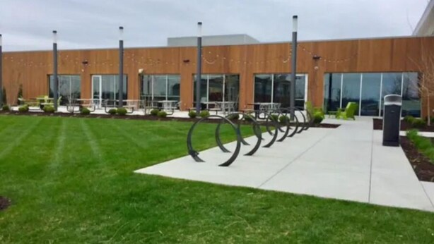 A modern building with a row of outdoor seating and a grassy area. - NEW Sleek, Contemporary Home Near Med School (Joplin)