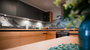 Una cocina moderna con salpicadero de temática montañosa, armarios de madera y horno empotrado.