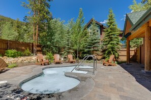 Relax in a serene hot tub surrounded by a patio with Adirondack chairs.