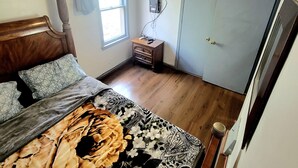 Een slaapkamer met een bed, een plafondventilator, een televisie, een dressoir en een deur.