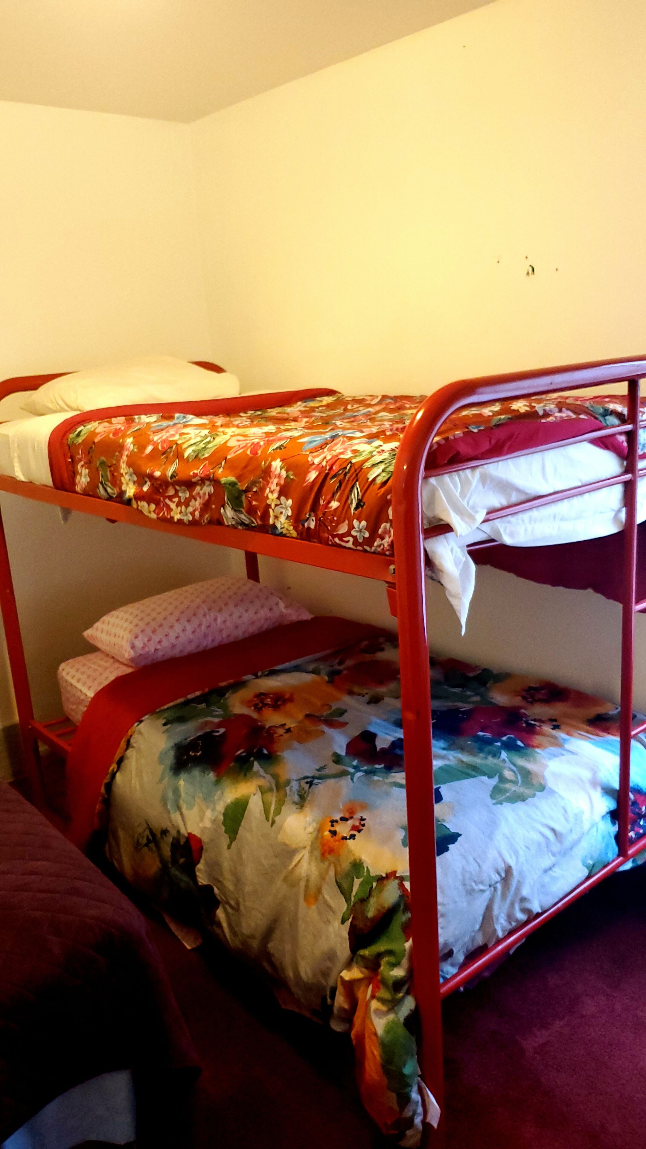 Ein Stockbett mit Blumenmuster und rotem Metallgestell.