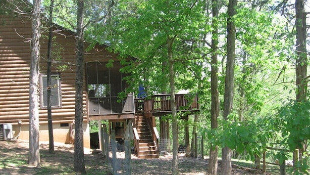A rustic cabin with a wooden deck and a staircase leading to a loft area. - Riverfront, pet friendly ! Log cabin with 2 bedrooms and loft! (Luray)