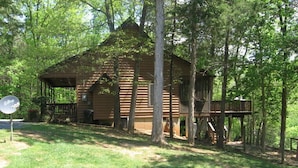 A rustic log cabin with a porch, surrounded by trees. - Riverfront, pet friendly ! Log cabin with 2 bedrooms and loft! (Luray)
