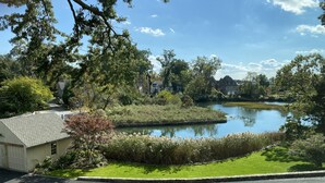 A residential area with a pond, houses, and a well-maintained lawn. - Luxury Home with Amazing Water Views - Perfect for an intimate family gathering (Mamaroneck)