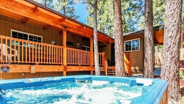 Een houten hut met een jacuzzi en een balkon.