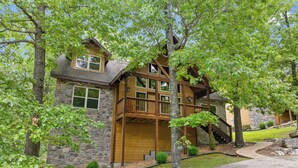 A two-story stone house with a wooden deck and a stone staircase. - Close to SCD, Both Indoor & Outdoot pools, Possum Tracks Lodge  4BR/4BA Lodge (Branson West)