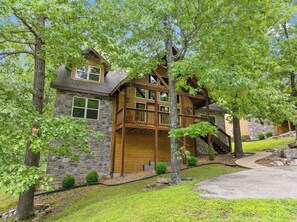 A two-story stone house with a wooden deck and a stone staircase.