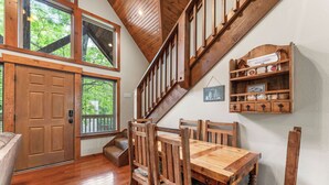 A wooden dining table with chairs, a wooden staircase, and a wooden door. - Close to SCD, Both Indoor & Outdoot pools, Possum Tracks Lodge  4BR/4BA Lodge (Branson West)