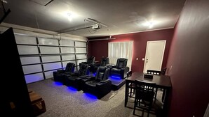 Une salle de cinéma privée équipée d’un grand écran, de plusieurs fauteuils inclinables et d’une petite table.