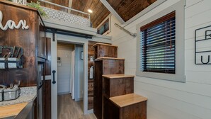 A modern kitchen with wooden accents, a built-in oven, and a countertop with utensils. - Newly Built Tiny House Near College Station and Round Top Area (Caldwell)