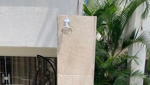 A vertical stone pillar with a metal door handle, a glass door, and a hammock chair in the background. - Beira Mar House in Angra dos Reis - Close to commerce in secure condominium (Angra dos Reis)